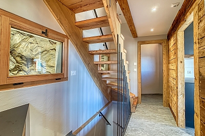 Entée, escaliers en bois, fenêtre avec vue sur le rocher éclairé